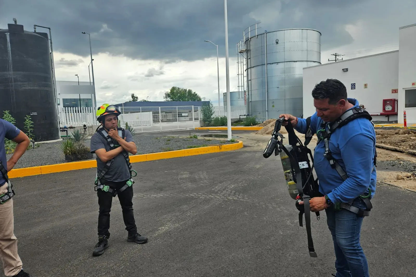 Instructor ajusta un equipo de respiración autónoma a un participante con arnés y casco durante la explicación previa