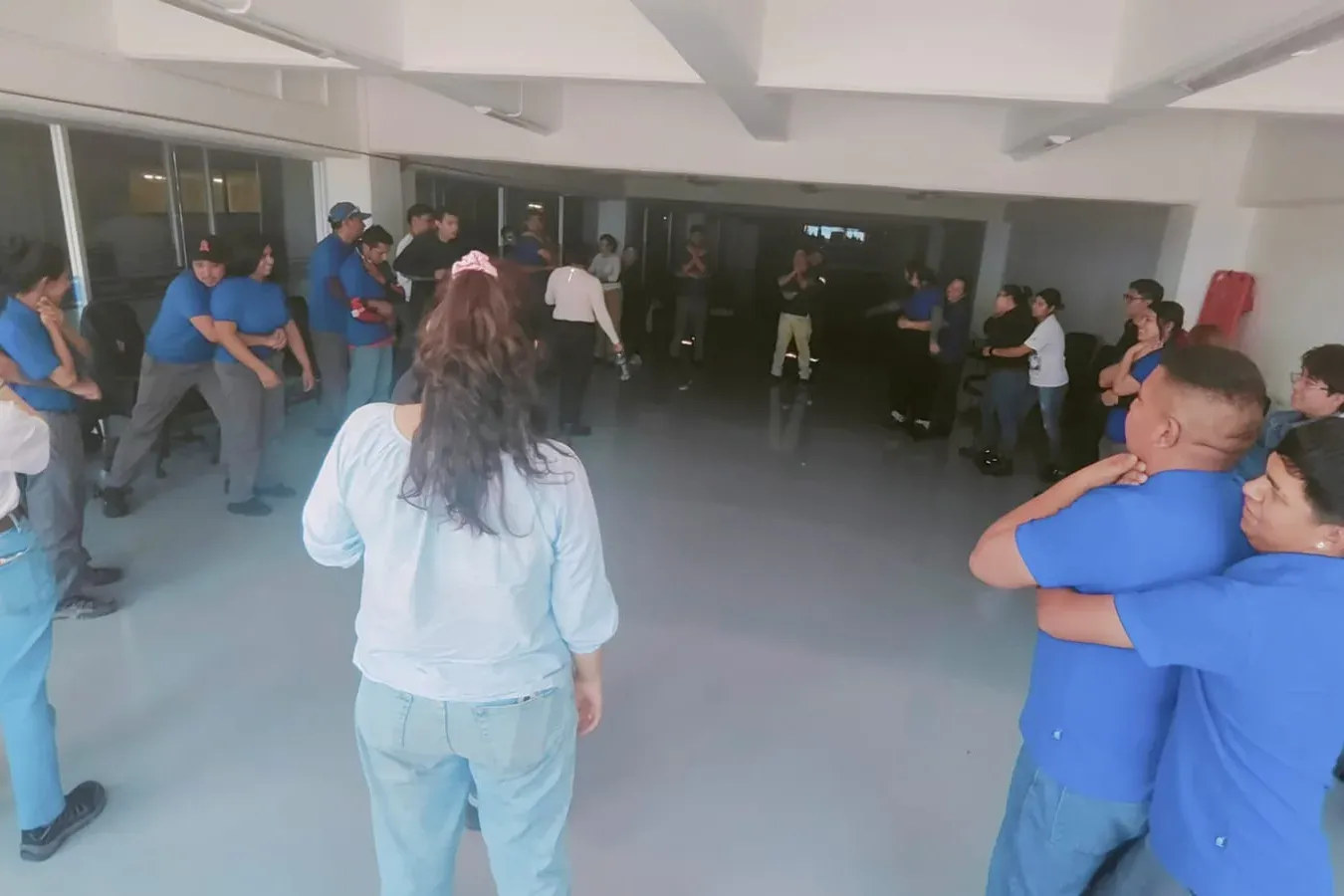 Participantes practican por parejas la maniobra de Heimlich en una sala mientras la instructora supervisa