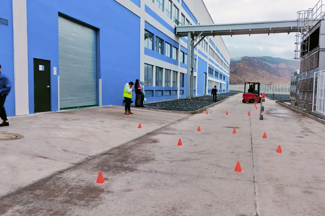 Montacargas real recorriendo un circuito de conos en el patio de una planta mientras los instructores supervisan